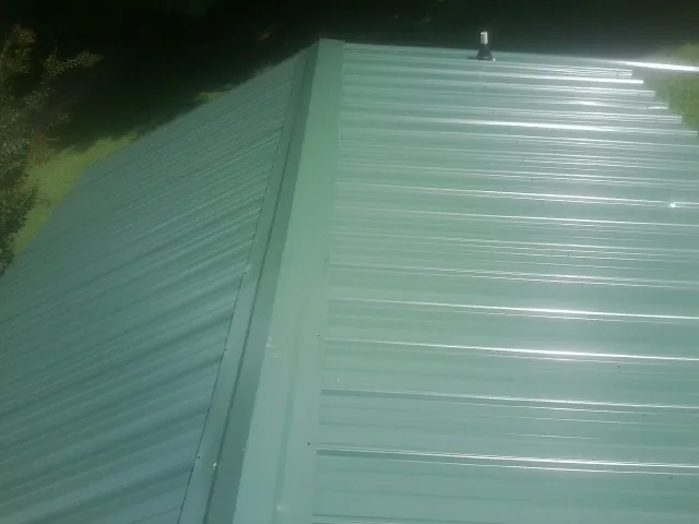 New green metal panels meeting at the ridge of a roof — Flat Roof Repair work by our crew in Archer